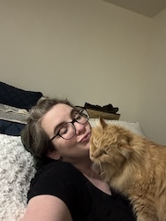An orange cat cuddles a woman