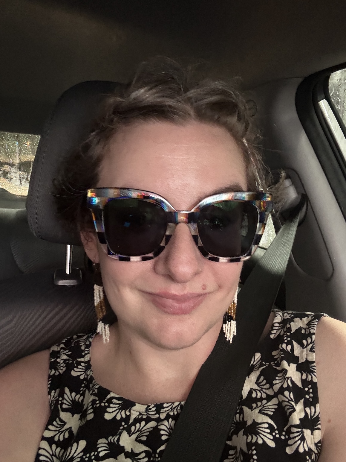 A woman in sunglasses smiles at the camera