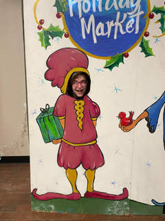 A woman grins behind a photo spot of an elf