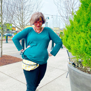 A woman stands with her hands on her hips wearing a fanny pack