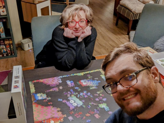 A man and a woman smile working on a puzzle